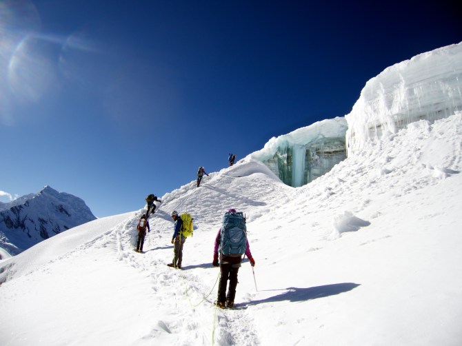 The team climes up around a beautiful open crevasse, on hard glacial ice. 